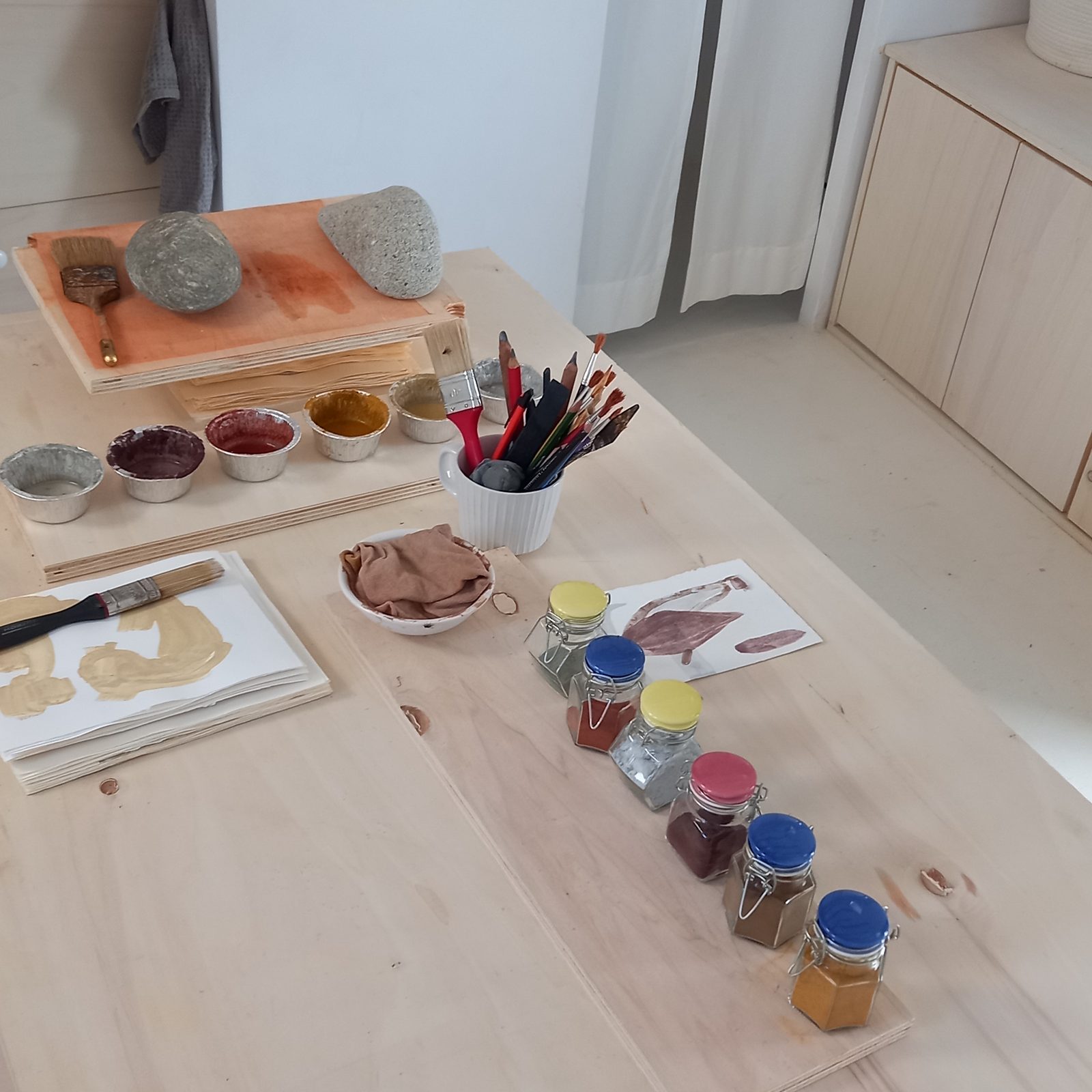 The studio table with jars of ground pigment, brushes and the stones they were made from