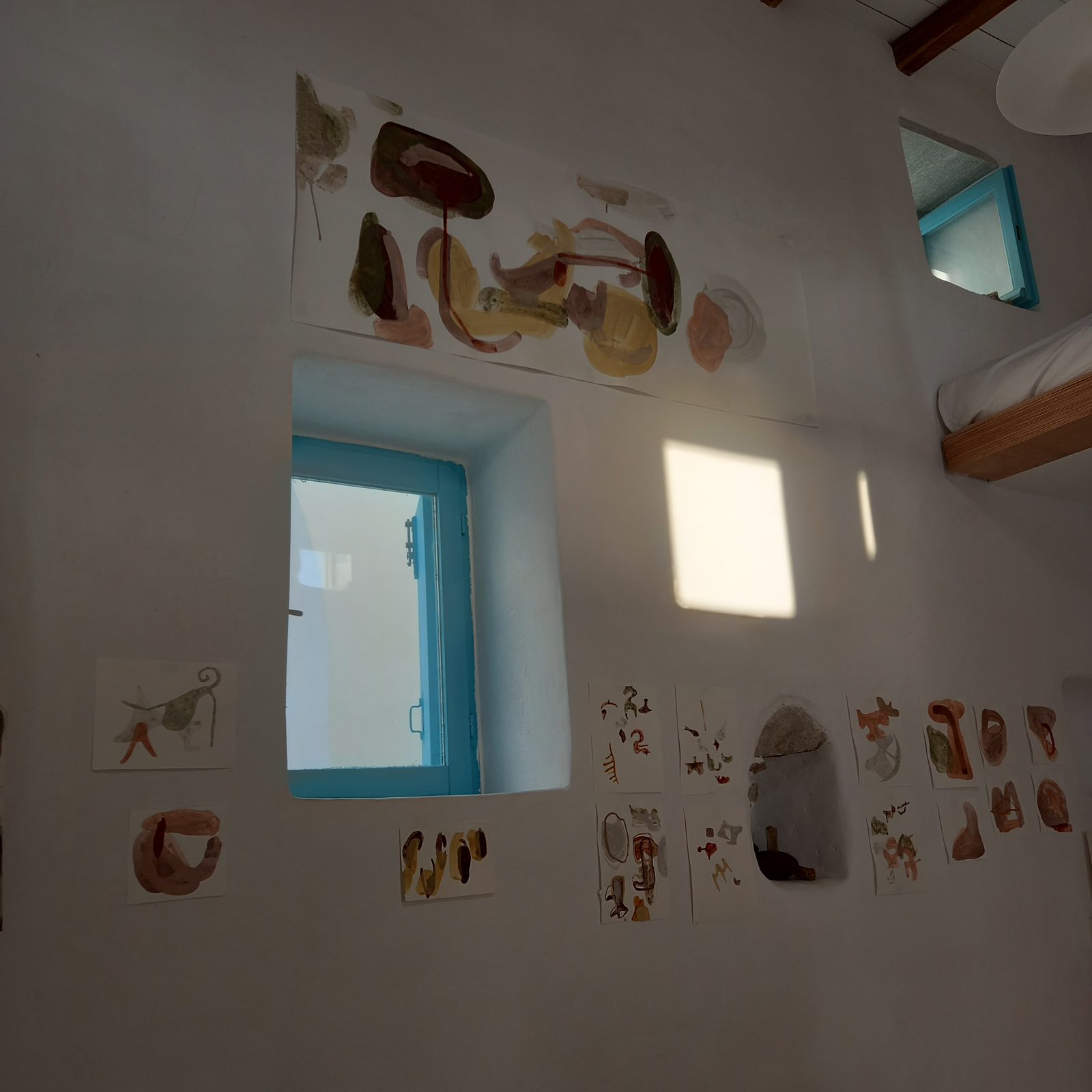 The whitewashed studio at Kotoki, its walls covered with small earth-pigment drawings around a blue window